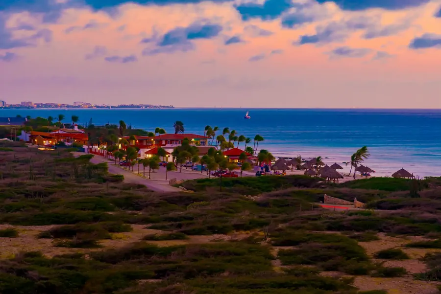 Die Küste von Aruba bei Sonnenuntergang mit einem langen Strand und türkisem Wasser