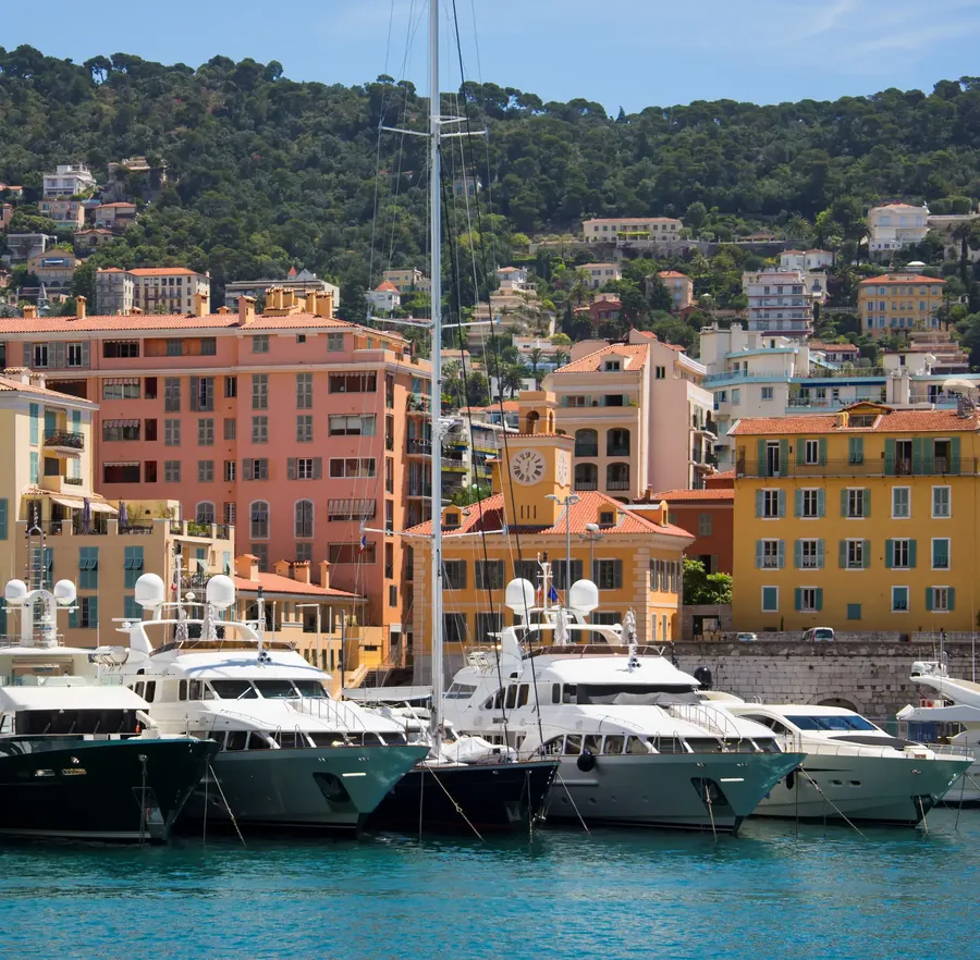 Der alte Hafen von Nizza mit ockerfarbenen Häusern, Booten und Hügeln dahinter