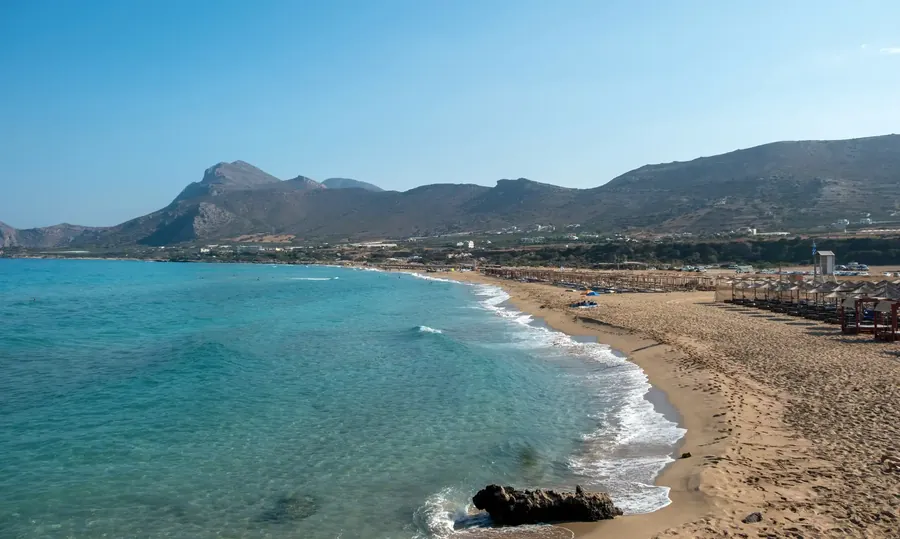 Der Strand Falasarna auf Kreta mit türkisem Wasser und Schirmen auf weißem Sand