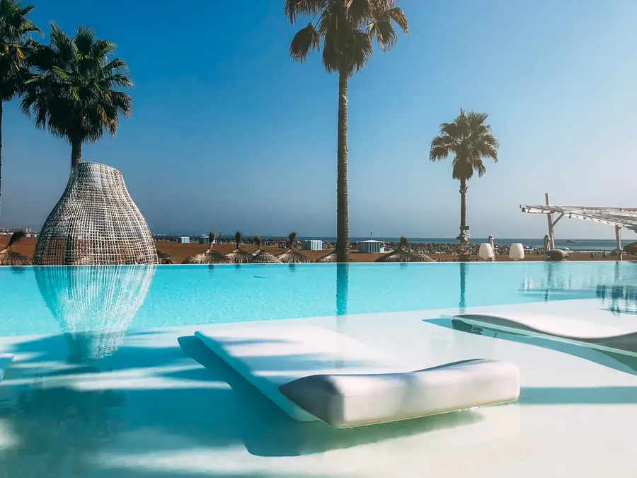 Ein Resortpool an einem Strand mit hohen Palmen