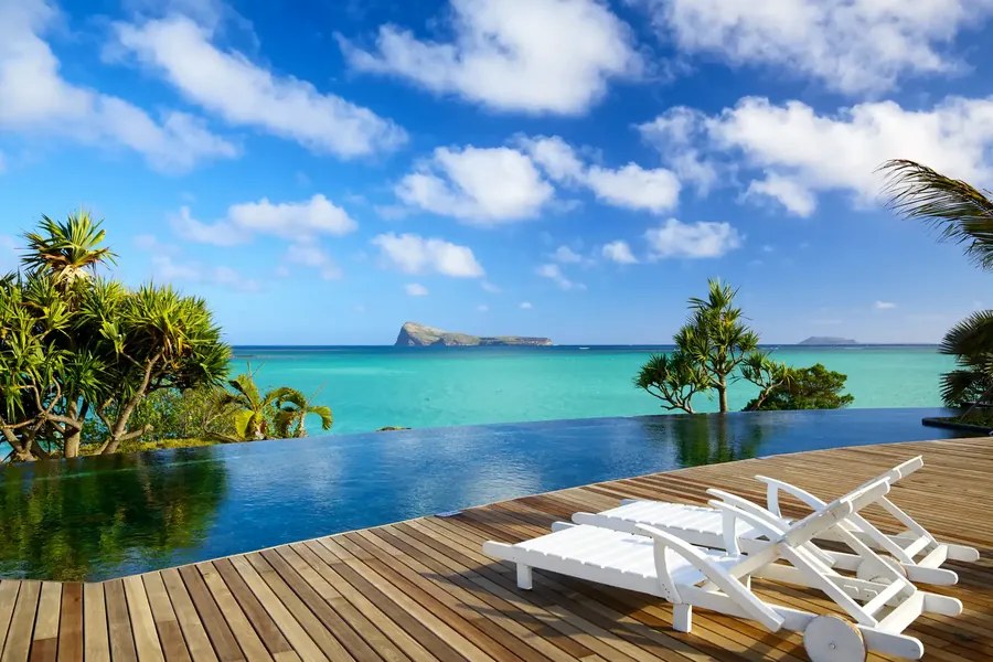 Ein Pooldeck unter Palmen mit Blick auf die Lagune von Mauritius