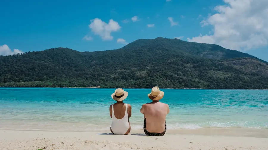 Koh Lipe mit türkisem Wasser, einem Longtail-Boot und einer grünen Insel dahinter
