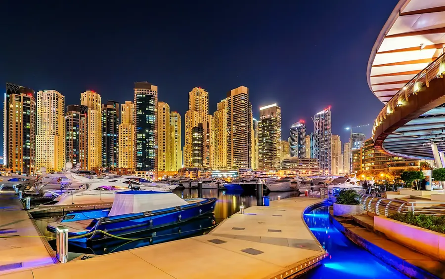 Dubai Marina bei Nacht mit beleuchteten Wolkenkratzern und Jachten