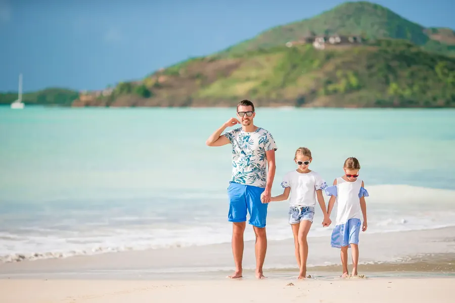 Ein Vater geht mit seinen zwei Töchtern am Strand