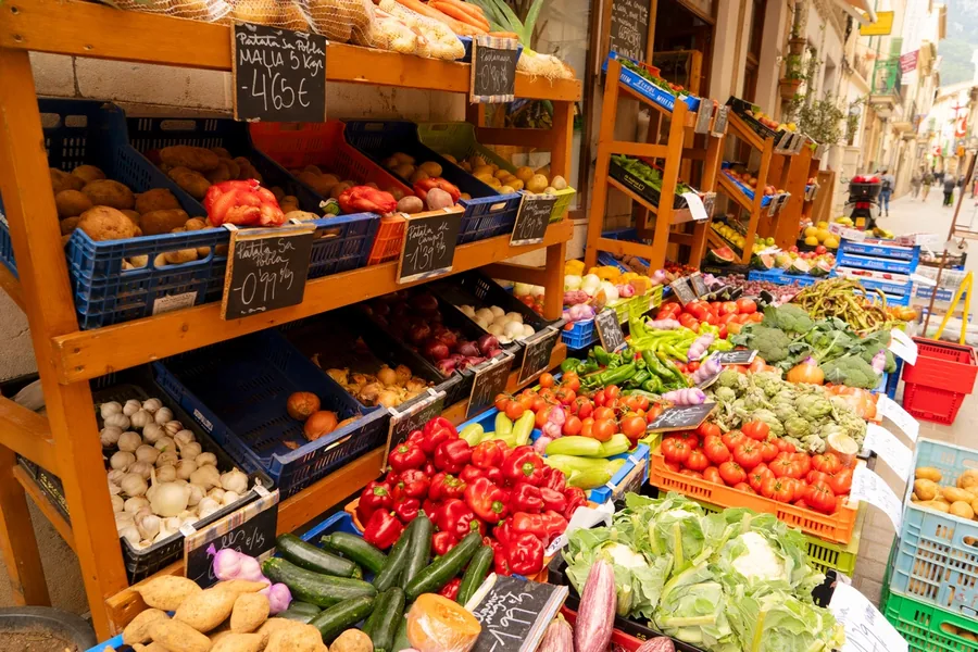 Marktstand mit Paprika, Tomaten, Kartoffeln und Kürbissen auf einem Wochenmarkt auf Mallorca